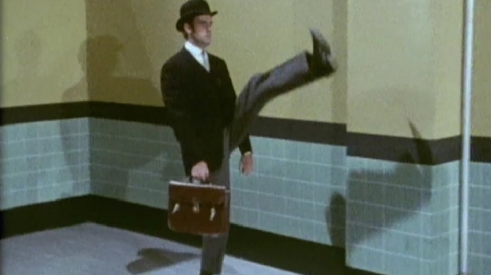 John Cleese z komediální skupiny Monty Python ve slavném skeči "Ministerstvo švihlé chůze".